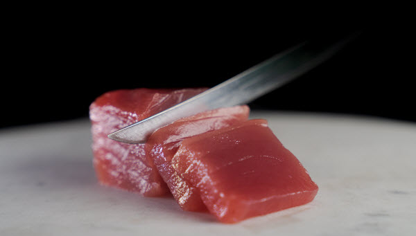 Knife slicing a tuna