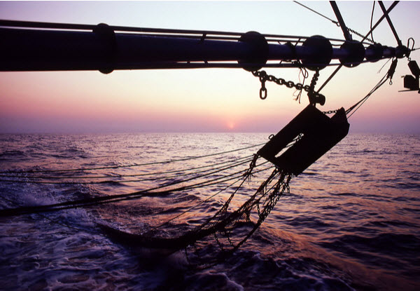 Dinko Tuna - Sustainable trawling View of a prawn trawler boom arm with otter boards and bottom trawling nets at sunset on the fishing grounds