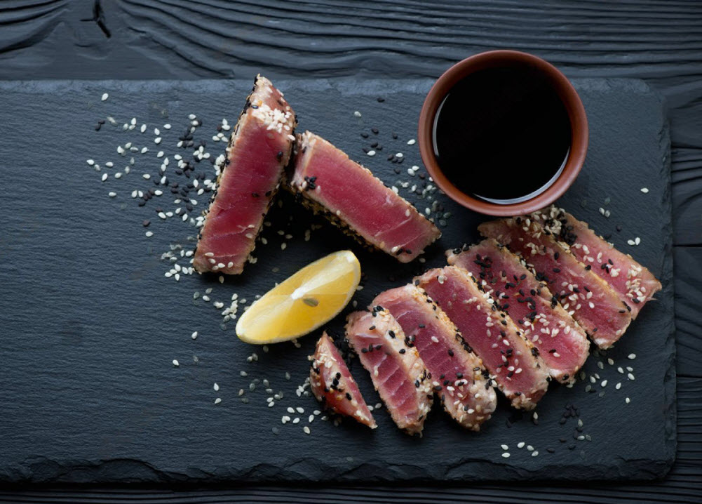 Stone slate tray with sliced tuna steak fried in sesame seeds