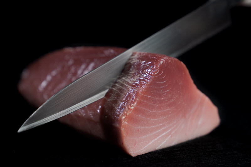 knife slicing a raw bluefin tuna