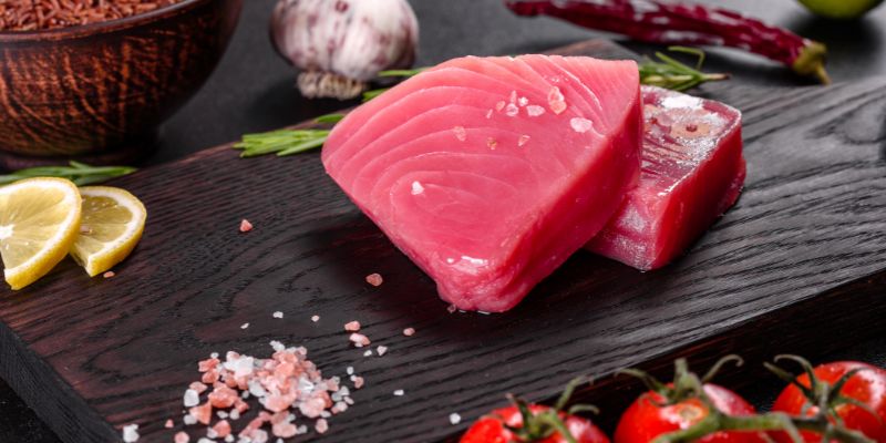 Fresh tuna fillet steaks with spices and herbs on a wooden plate