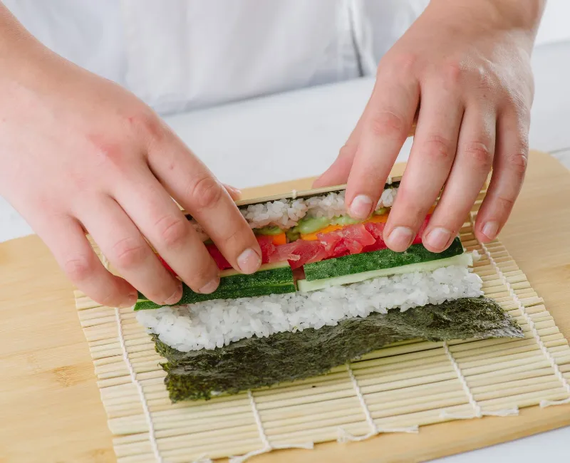 cook prepares sushi and wraps