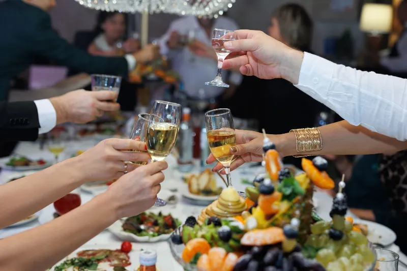 People with champagne in their hands at the festive table.