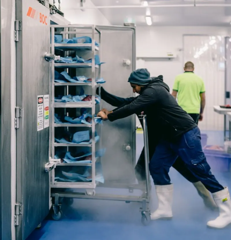 man pushing a rack back to the freezer