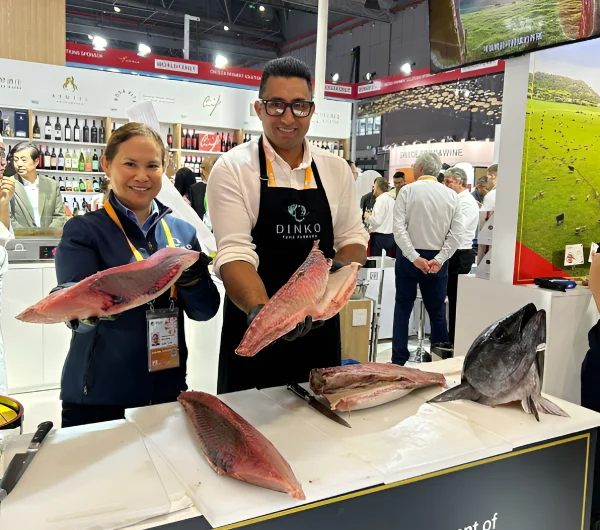 Two people holding tuna fish at a stall